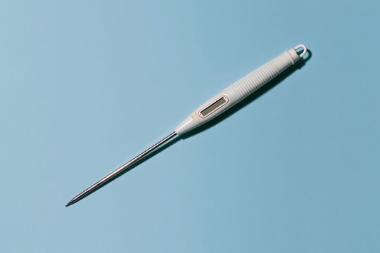 Kitchen thermometer with a polished steel probe and ribbed grip, lying diagonally on a bright blue background with copy space for a product mockup
