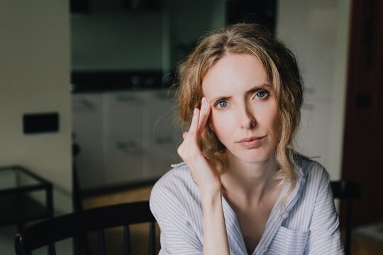 Thoughtful woman touching her temple while experiencing mental fatigue and cognitive overload at home