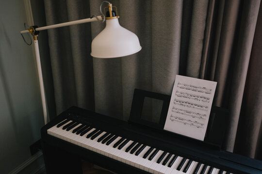 Digital piano with sheet music and reading lamp arranged for music practice at home