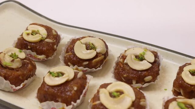 Dodha barfi garnished with cashews on a white plate