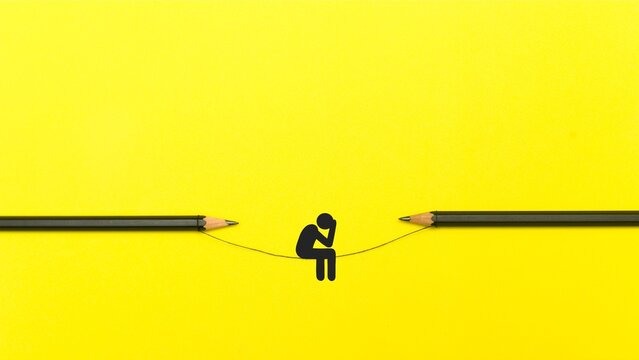Conceptual minimalist photo of a paper stick figure sitting on a thin wire between two black pencils against a bright yellow background, symbolizing risk, focus, stress, or balance.