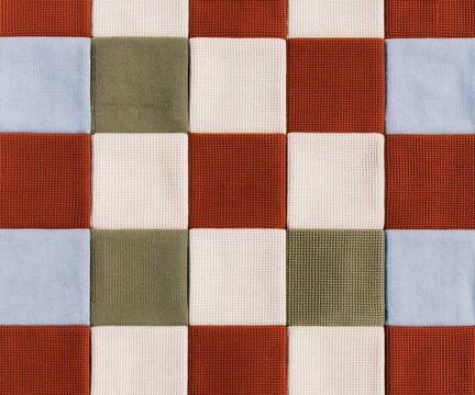 Folded throws in a grid of olive green, maroon, cream, and pale blue, featuring tactile ribbed and waffle textures for a textile colorway guide