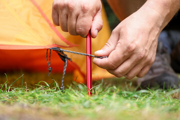 Tourist putting up tent and securing it with stake at campsite, closeup © New Africa