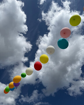 Colorful Baloons hanging in a blue and cloudy sky