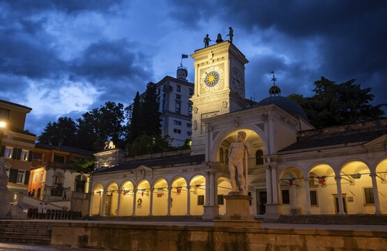 Illuminated main square Piazza della Libert&agrave; with Loggia e Tempietto di San Giovanni and clock tower, Castello di Udine behind, blue hour, dramatic sky, old town, Udine, Friuli-Venezia Giulia, Italy