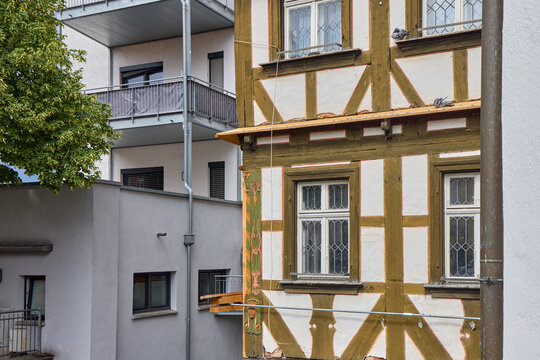 Contrast between old half-timbered house and modern white residential building with balconies in Germany, dark stormy sky in background, street architecture in Forchheim, Bavaria.