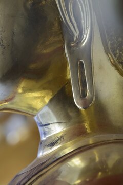 The photo shows a section of the left earlobe of a gilded Buddha statue, the gilding shows fine signs of wear, matte areas and subtle reflections that accentuate the materiality of the statue. The transition from ear to neck region is visible, with soft, harmonious contours typical of the stylized representation of the Buddha, the image gives the impression of a silent, concentrated detailed study of an iconographic feature of Buddhist sculpture, Wat Suthat Thepwararam, Royal Temple, Phra Nakhon, Bangkok, Thailand
