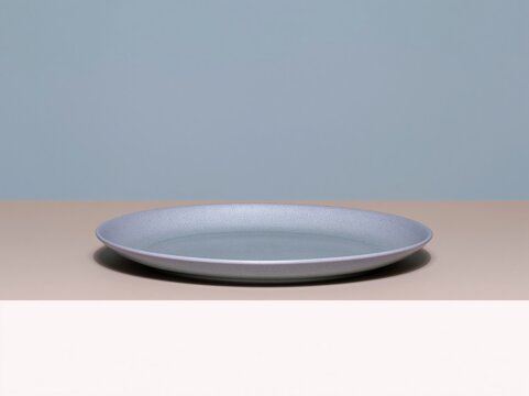 Empty blue ceramic dinner plate with a smooth glaze and subtle texture, presented on a neutral gradient background for kitchenware catalogs and food styling