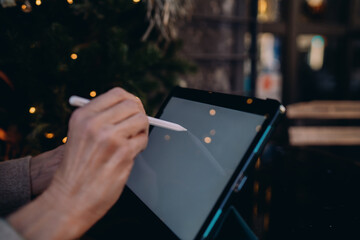 Macro shot of stylus pen touching digital tablet display, creative professional sketching on portable device, high tech illustration tool, electronic design process, blurred outdoor background. © BullRun