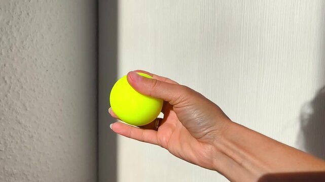 Hand squeezing a bright yellow squishy toy with a smiling face, showcasing the gradual compression and deformation of the object in a well-lit indoor setting