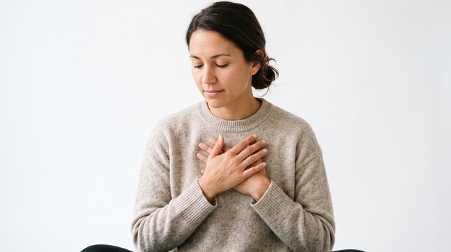 Woman with hands on chest in meditative pose expressing gratitude and peace