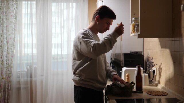 Vertical video man standing in a modern kitchen, viewing a digital recipe on a tablet screen, embodying digital lifestyle and smart home technology while preparing a meal