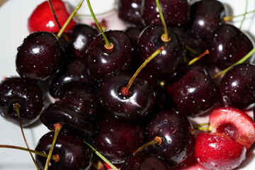 Close-up of juicy ripe cherries with green stems ready to eat, with copy space for text. Detailed food shot of sweet red berries. © Edita