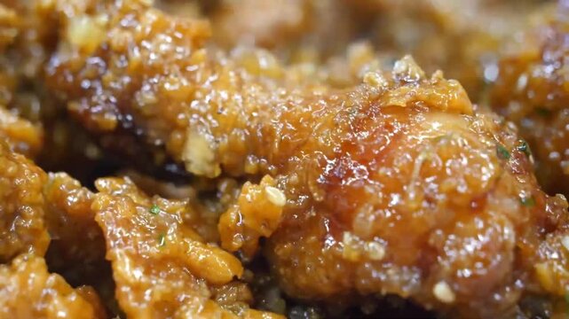 Close-up macro footage of crispy Korean fried chicken coated in a sticky, sweet and spicy gochujang glaze with shallow depth of field.
