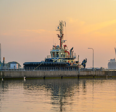 Gothenburg, Sweden - June 28 2026: Tugboat moored beside industrial pier in warm sunset light.