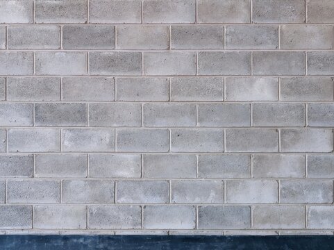 Painted breeze-block wall in charcoal and neutral grey with a coarse chalky texture and deep shadows, providing a raw background for posters and templates