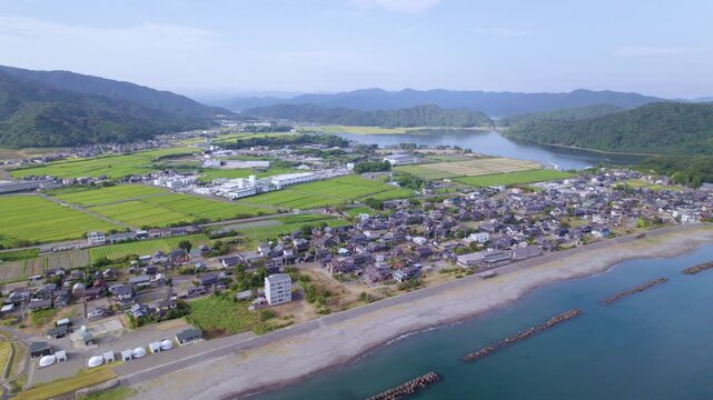 松原の集落と奥の湖を見下ろしながら右へ横移動する空撮 / Drone tracking right over a village