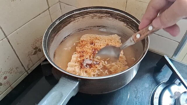 Instant noodle soup cooking in metal pot