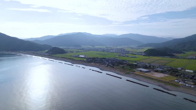 海と松原の海岸線を左へ大きく旋回して見下ろす空撮 / Drone orbiting left over the coast