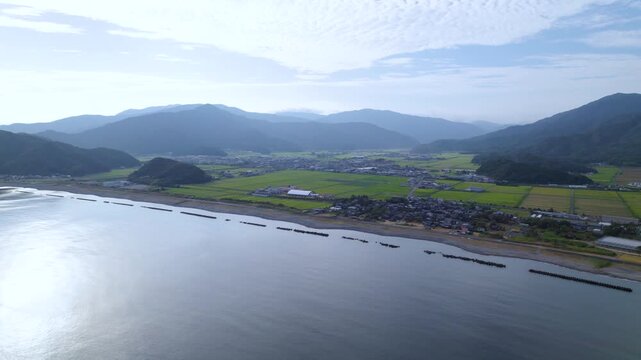 高空から松原の美しい海岸線と町並みに沿って前進する空撮 / Drone flying forward over the coastline