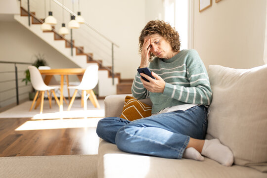 Woman feeling stressed having headache reading bad news on phone