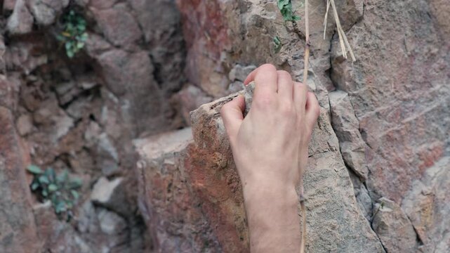 Rock climber hands gripping rocky mountain cliff