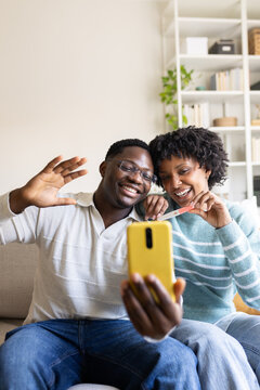 Happy couple sharing pregnancy test result on video call