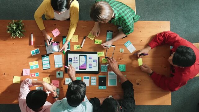 Programmer sharing Ux Ui design for mobile phone interface idea with software developer while designer writing idea at sticky notes. Start up team develop wireframe prototype. Time lapse. Convocation.