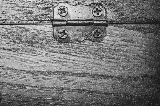 Black and white macro of antique metal hinge with screws on wood