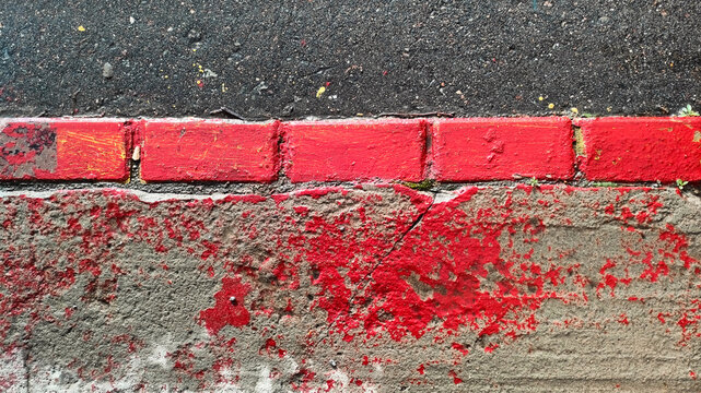 Urban macro texture with red painted block and grey concrete with scattered paint marks