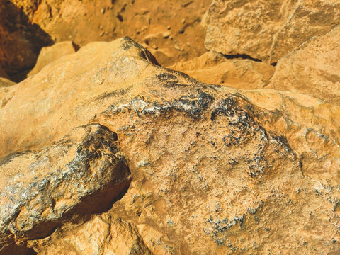 Rough orange sandstone texture with dark mineral patches