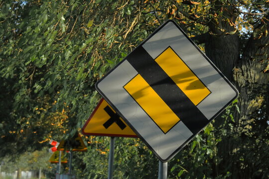 Polish no priority sign with other signs in background against green foliage backdrop