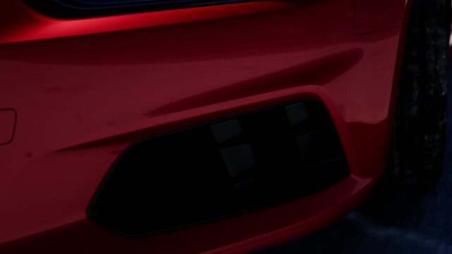 The scene shows a close up of a red cars rear detail at night. The area is dimly lit, highlighting the sleek lines and a black vent on the side. There are no other objects nearby.