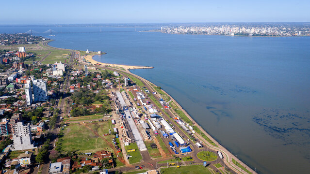 Wide aerial shot of Encarnacion's waterfront with a distant bridge connecting to Posadas skyline.
