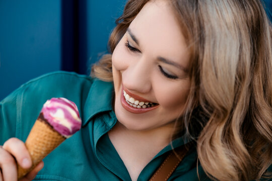 Happy mature woman holding delicious ice cream cone enjoying summer hot weather, carefree adult treating herself with sweet dessert, relaxed female finding everyday joy in simple lifestyle moments