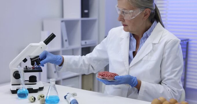 Quality control. Scientist in protective goggles and gloves working at white table with products in laboratory. Camera moving forward