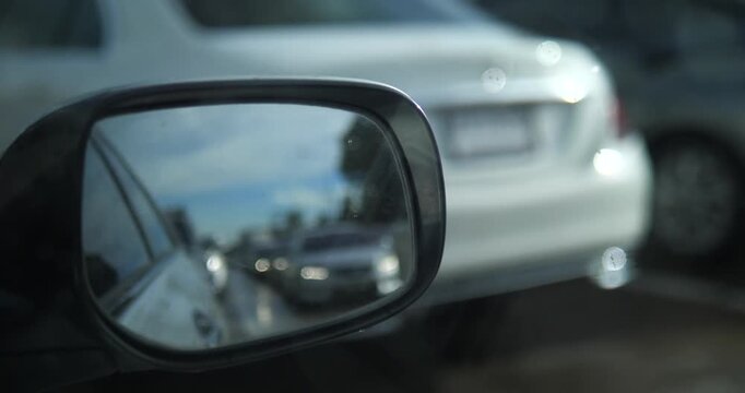 Close up of car side rear view mirror reflecting traffic on road