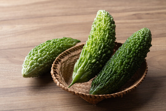 Fresh bitter gourd or bitter melon in a basket on a wooden background, Asian vegetables and herbal medicine