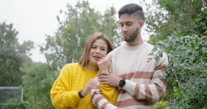 African American couple standing in park, woman speaking to camera, leaning close in yellow sweater
