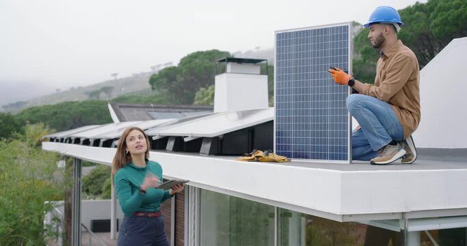 African American homeowner pointing tablet while installer kneeling installing solar panel on roof