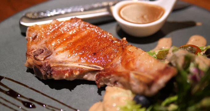 Close up of grilled juicy pork chop steak with brown gravy sauce in restaurant