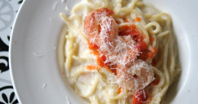 Close up of creamy fettuccine Alfredo pasta with shrimp and grated parmesan cheese