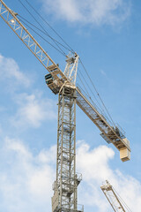 Operator cabin and metal mast of a tall tower crane working on a high-rise building construction site in the city. © AncientAftertone