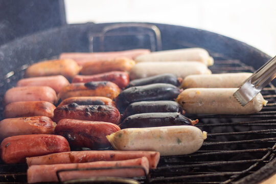 Grilling assorted sausages and blood sausage on barbecue