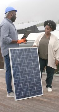 Vertical video: Installer checking tablet pointing at panel as client asking about install on roof