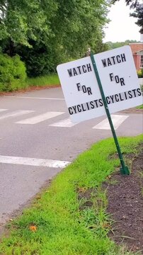 Cyclist Riding Past "Watch For Cyclists" Road Safety Sign at Crosswalk in Lexington, Massachusetts