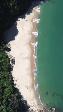 Overhead view of waves breaking on a sandy beach in the Caribbean. Vertical