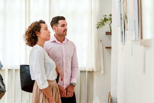 Two people viewing art in a gallery, standing side by side.
