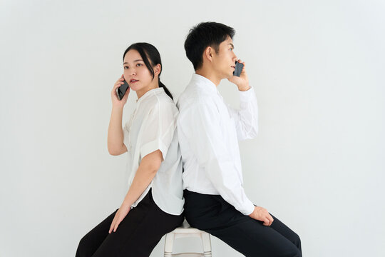 Young Japanese Man and Woman Back to Back Using Smartphones