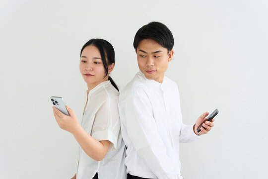 Young Japanese Man and Woman Back to Back Using Smartphones
